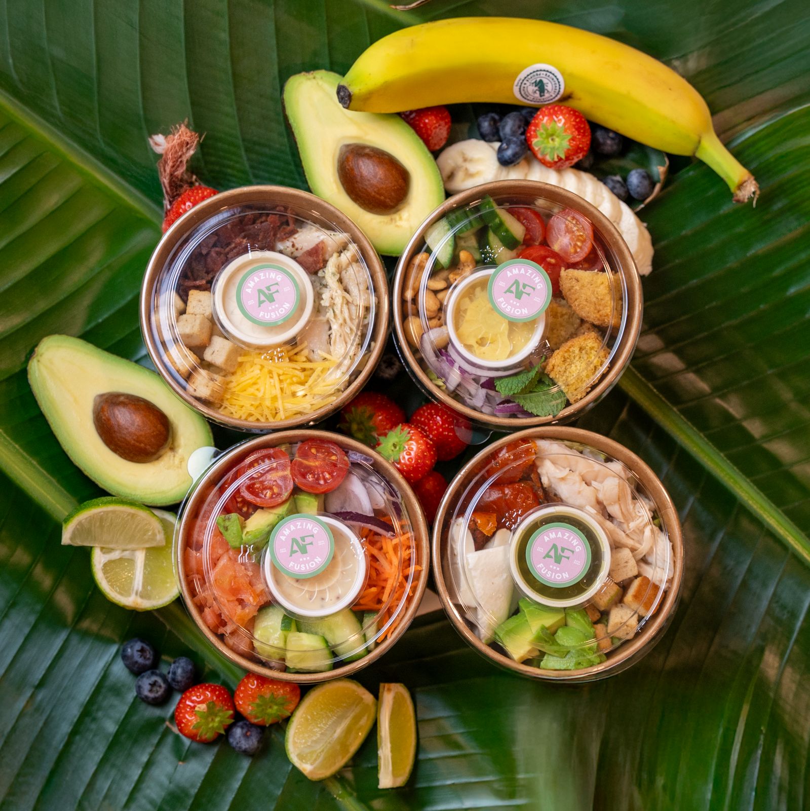 Rijstbowls van Amazing Fusion omringd met kleurrijk vers fruit, geserveerd op een stijlvolle schaal.